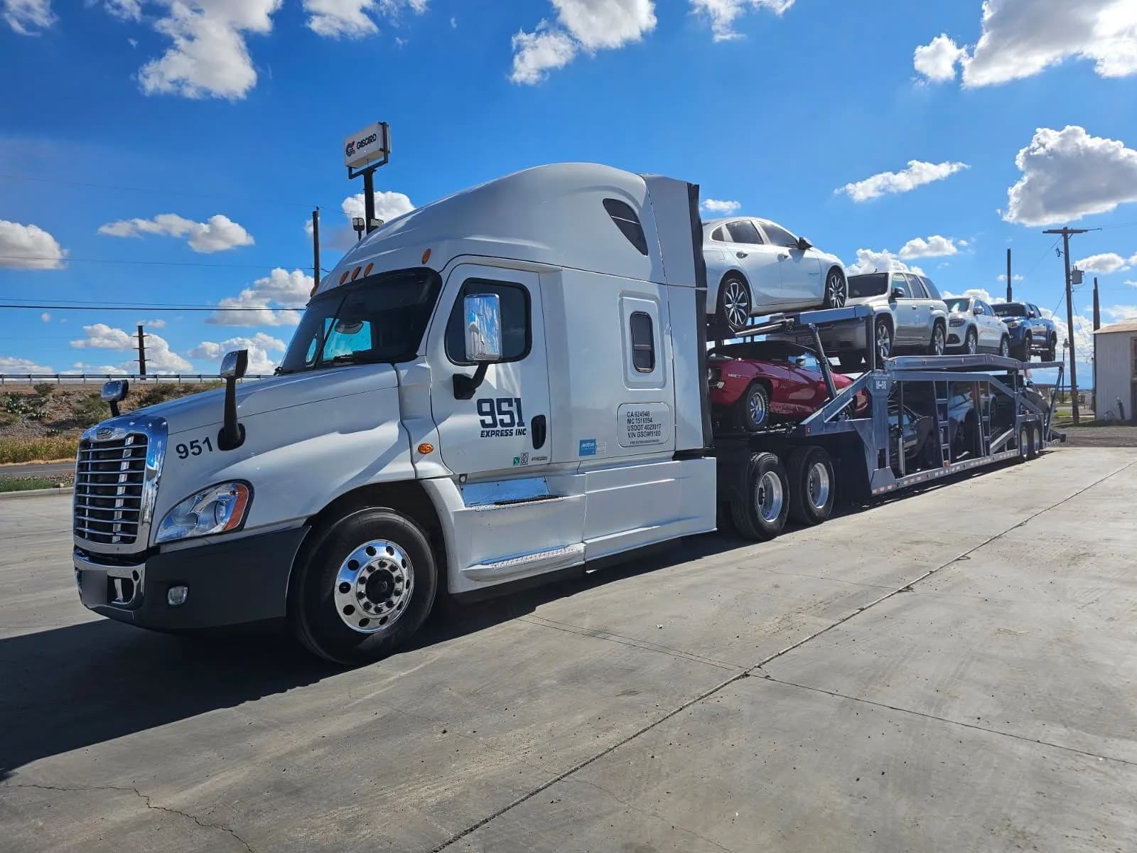 A white 951 Express car hauler loaded with sedans, SUVs, and a classic car.
